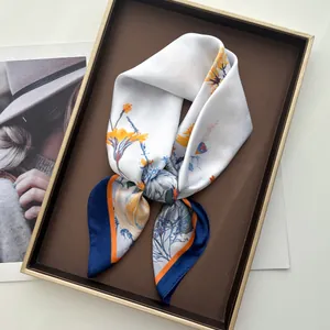 Detailed view of floral silk scarf with yellow flowers and blue border in a luxury gift box