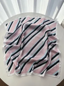 Detailed view of striped silk scarf texture with pink, black, and blue diagonal patterns