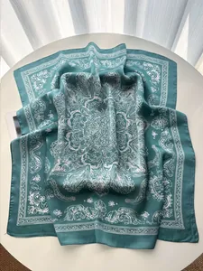 Detail of teal silk scarf with white mandala patterns and smooth satin finish texture