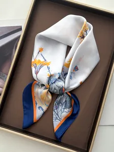 Detailed shot of floral print silk scarf with blue borders in an elegant tray setting
