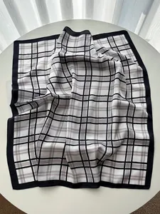 Detailed view of the black and white plaid silk scarf with elegant satin finish and wide hem