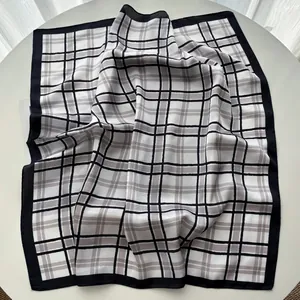 Close-up of classic black and white plaid silk scarf with detailed hem and smooth texture