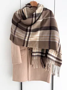 Détail d'une écharpe à carreaux classique avec pompons sur un manteau de laine d'hiver