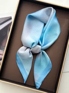 Gros plan d'un élégant foulard en soie dégradé bleu et gris dans son coffret cadeau chic