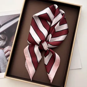Close-up of geometric striped silk square scarf with burgundy and black pattern in a tray