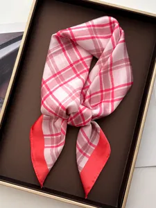 Close-up of elegant pink plaid silk-like scarf with red border in a premium gift box