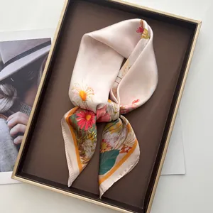 Detail showing silky champagne floral scarf with red daisies in a gold display tray