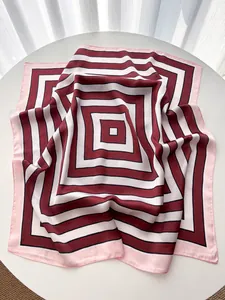 Detailed close-up of striped silk square scarf with red and pink geometric patterns