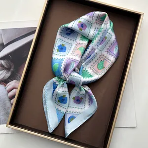 Détail d'un foulard en satin de luxe avec motifs floraux dans un coffret cadeau doré