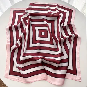 Detail of a square silk scarf featuring a geometric pattern in burgundy, black, and white
