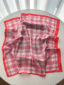 Close-up of red and grey checkered silk scarf folded on a table with soft lighting