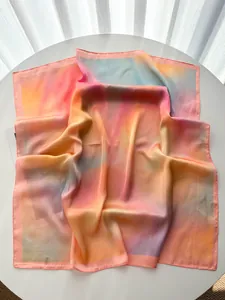 Détail d'un carré en soie dégradé multicolore avec bordure roulée sur une table