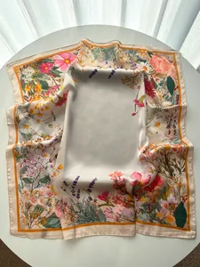 Detailed close-up of a satin square scarf featuring floral prints and orange edges
