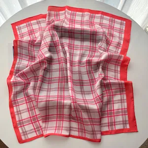 Detailed view of red and white plaid silk scarf showing smooth texture and edge stitching