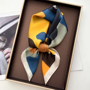 Elegant geometric patterned silk square scarf in blue and yellow on display tray