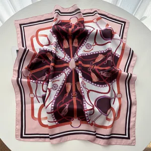Detail view of pink silk scarf featuring elegant equestrian tassel and chain print patterns