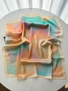 Détail d'un foulard carré en satin soyeux avec dégradé aquarelle coloré et larges bords crème