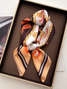 Detail of silk scarf with luxury chain and tassel print tied in a gift box