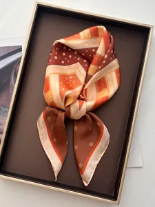 Detail eines Satin-Halstuchs mit orangefarbenem Sternenmuster und Polka-Dots auf Tablett
