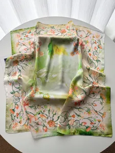 Dettaglio di sciarpa in seta floreale con fiori d'arancio vibranti e stampe di viti