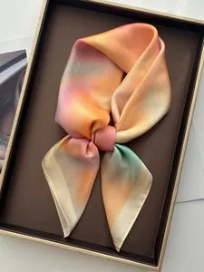Gros plan détaillé d'un foulard en soie dégradé avec bords roulés fins sur plateau cuir