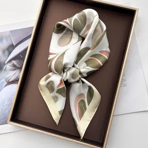Detailed view of leaf pattern silk scarf tied in a bow on a brown display gift box