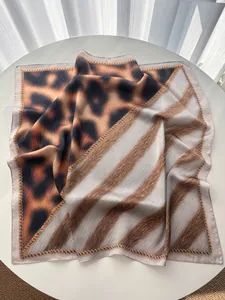 Detail of premium leopard print and striped silk-feel square scarf on white table