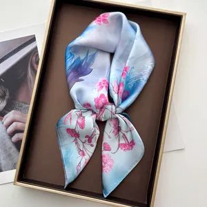 Dettaglio di sciarpa in seta azzurra con fiori rosa in una scatola regalo di lusso