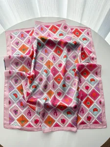 Détails d'imprimés tropicaux sur un foulard en satin rose avec motifs palmier et homard