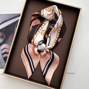 Detail of luxury silk scarf with gold chain and tassel print inside a golden gift box