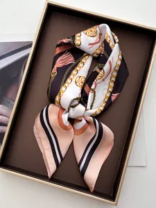 Detailed view of luxury silk scarf featuring golden chain and tassel prints on a display tray