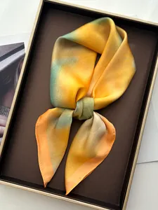 Détail d'un foulard en soie dégradé jaune et vert présenté dans un coffret cadeau