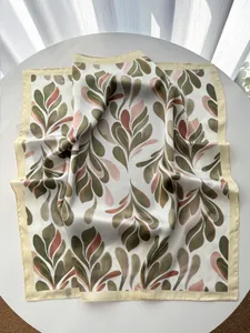 Detail of silk-like square scarf featuring elegant olive leaf prints and smooth texture