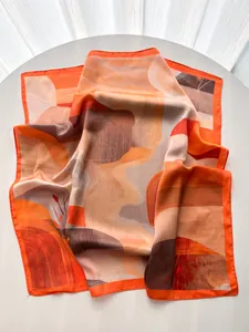 Close-up of abstract mountain pattern on elegant silk scarf with orange and beige tones