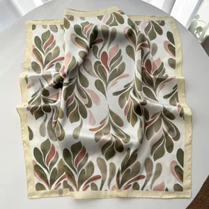 Detail of silk square scarf featuring olive green leaf patterns and elegant satin texture