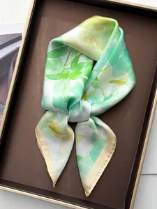 Detailed texture of watercolor floral silk scarf with hand-rolled edges on leather tray