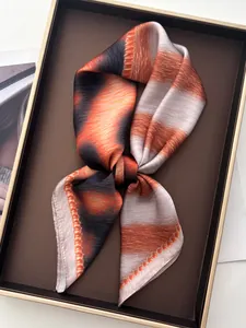 Detail of silk-like scarf with orange and grey gradient stripes in a display tray
