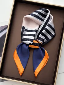 Vue détaillée d'un foulard en soie géométrique avec des bords roulés sur un plateau