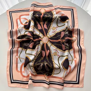 Detail of silk square scarf featuring chain tassels and equestrian patterns in coral and black