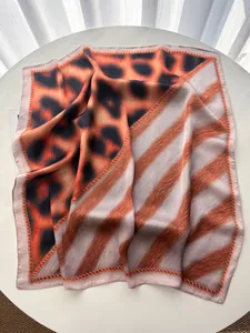 Detailed view of large square silk scarf featuring leopard print and orange stripe patchwork