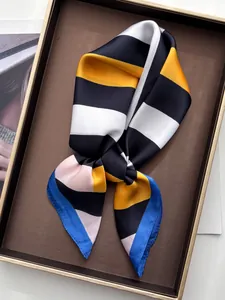 Detail of silk-like square scarf with geometric stripe patterns in leather display box