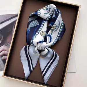 Detail of silk satin scarf featuring navy blue chain and tassel print in a luxury gift box