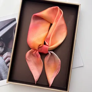 Carré en soie élégant avec dégradé rose et orange sur un plateau de luxe pour femme