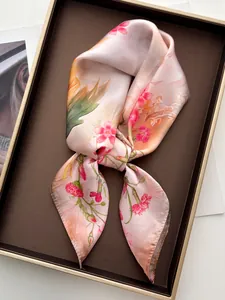 Dettaglio di un foulard di seta rosa con fiori in una lussuosa confezione regalo