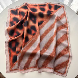 Detail view of leopard and stripe print silk scarf with fine rolled edges on white table