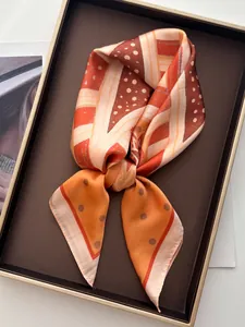 Nahaufnahme eines Seidenschals mit orangefarbenen geometrischen Mustern und Punkten