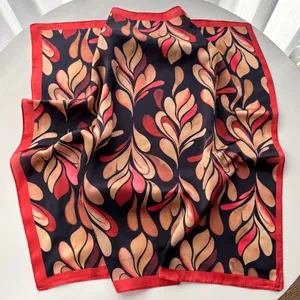 Detail of artistic floral pattern on square silk scarf with elegant red border trim