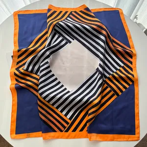 Détail du foulard carré en soie avec bordure orange et motifs géométriques bleu marine
