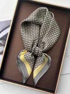 Détail d'un foulard en soie noué avec des motifs géométriques et des tons jaunes