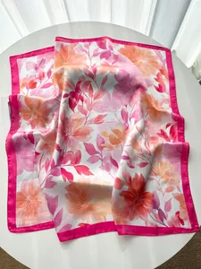 Detailed view of french style peony silk scarf with magenta borders on a white table